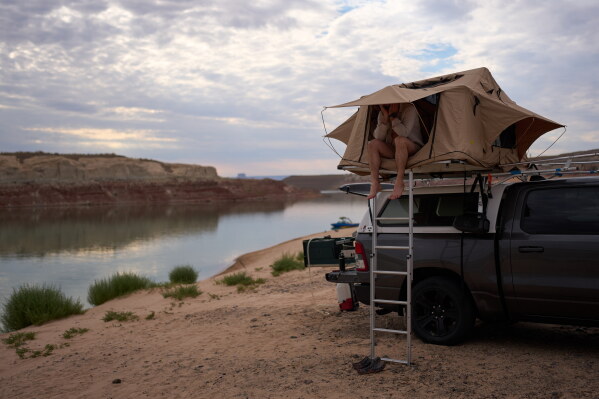 Mark Budzko rubs his eyes as he wakes up while camping beside Lake Powell at the Glen Canyon National Recreation Area, Wednesday, July 15, 2026, near Big Water, Utah. (AP Photo/John Locher)