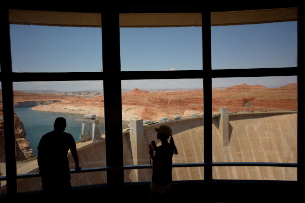 People look at the Glen Canyon Dam, Tuesday, July 14, 2026, near Page, Nev. (AP Photo/John Locher)