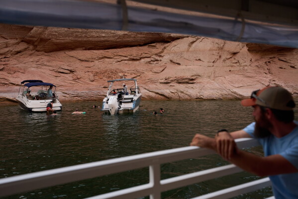 Boaters swim in a canyon on Lake Powell at the Glen Canyon National Recreation Area, Wednesday, July 15, 2026, near Page, Ariz. (AP Photo/John Locher)
