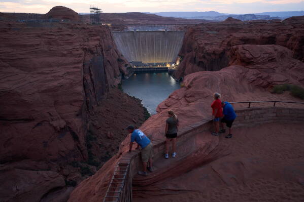 People view the Glen Canyon Dam from a viewpoint above the Colorado River, Tuesday, July 14, 2026, in Page, Ariz. (AP Photo/John Locher)