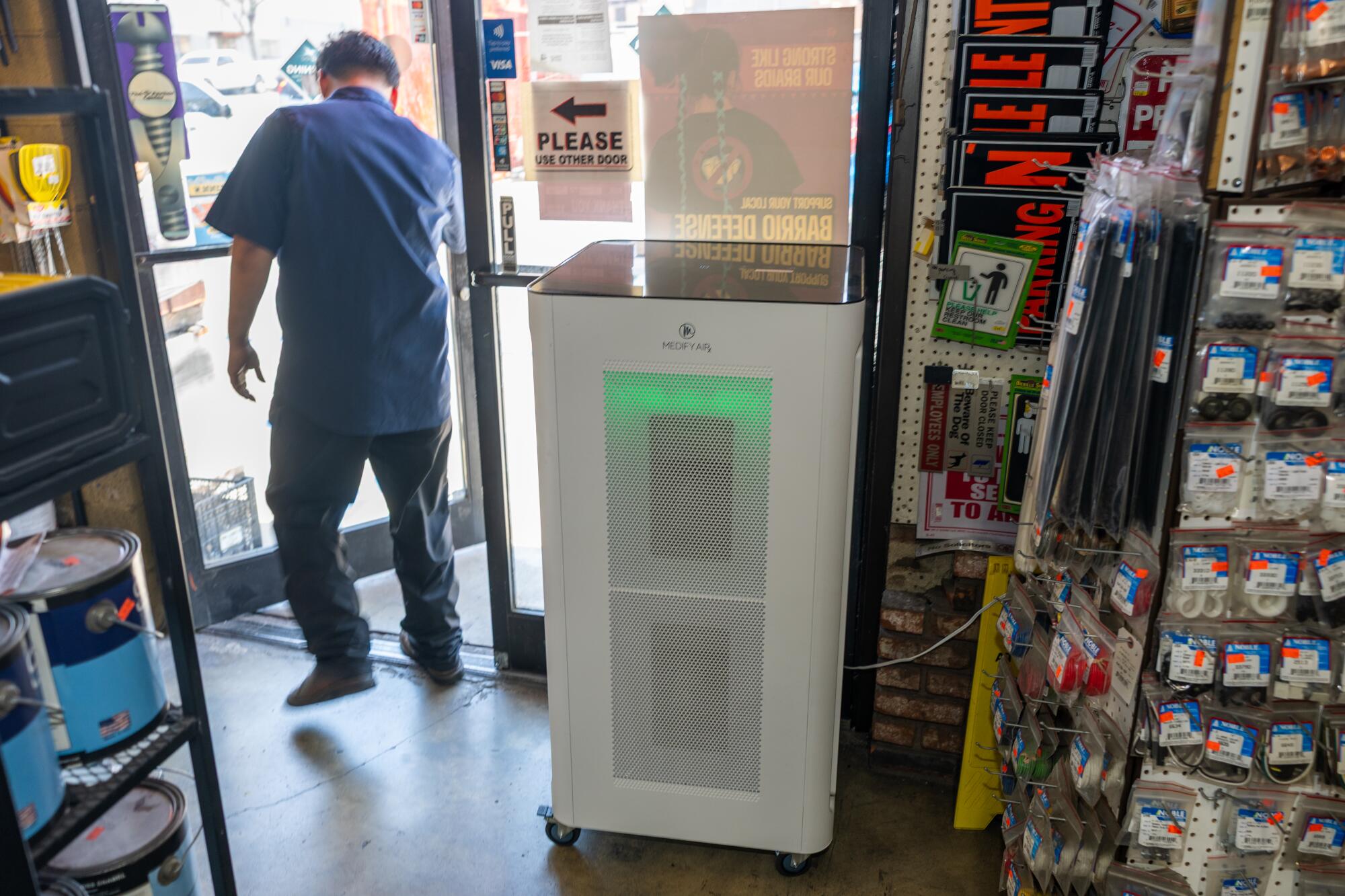 Bryan Regis walks past his business' air purifier that was supplied by the South Coast AQMD.