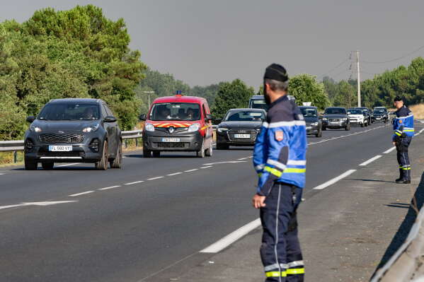 People leave the Ares region during wildfires, western France, Friday July 24, 2026. (AP Photo/Caroline Blumberg)