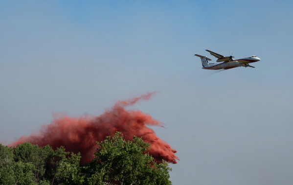 A water bomber drops water while fighting wildfires In Ares, western France, Friday July 24, 2026. (AP Photo/Caroline Blumberg)