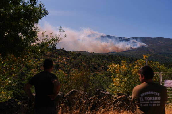 Smoke and flames rise as a wildfire advances near Burgohondo, Ávila province, Spain, Friday, July 24, 2026. (AP Photo/Manu Fernandez)