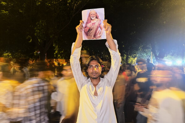 A protestor holds a placard with a portrait of Indian Prime Minister Narendra Modi draped in a saree, a traditional garment for women in India, during a demonstration demanding educational reforms as part of the Cockroach Janta Party's ongoing protest movement in New Delhi, India, Thursday, July 23, 2026. (AP Photo/Verda Subzwari)