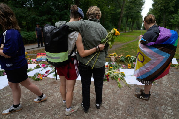 Two people hug at the memorial site commemorating the victims near the scene where a car rammed into a crowd at the Pride March in Berlin, Germany, Sunday, July 26, 2026. (AP Photo/Markus Schreiber)