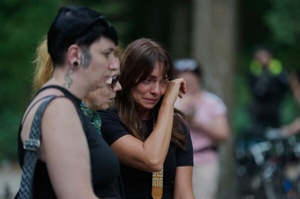 People attend the memorial site commemorating the victims near the scene where a car rammed into a crowd near the Pride March in Berlin, Germany, Sunday, July 26, 2026. (AP Photo/Markus Schreiber)