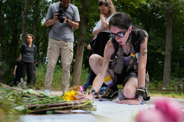 Ashley Jump lays flowers near the scene where a car rammed into a crowd near the Pride March in Berlin, Germany, Sunday, July 26, 2026. (AP Photo/Markus Schreiber)