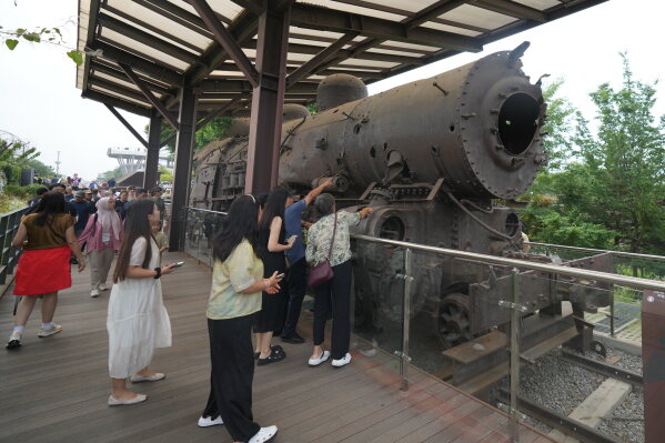 Tourists look at a steam train that was damaged during the Korean War, is displayed at the Imjingak Pavilion in Paju, South Korea, Saturday, July 4, 2026. (AP Photo/Lee Jin-man)