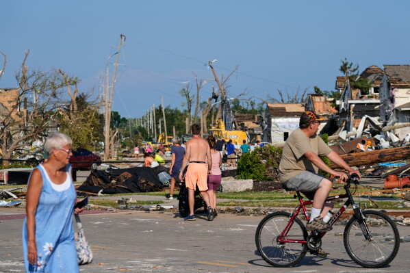 People walk among debris after a tornado struck Monday, July 27, 2026, in Menasha, Wis. (AP Photo/Kayla Wolf)