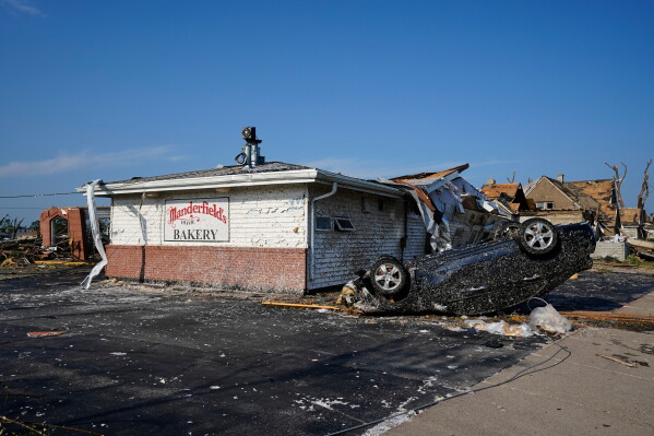 An upside down car sits in front of a damaged bakery after a tornado struck Monday, July 27, 2026, in Menasha, Wis. (AP Photo/Kayla Wolf)
