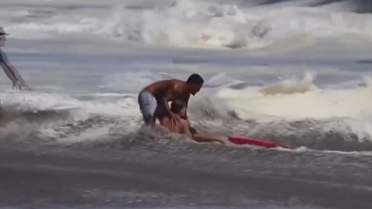 man pulls lifeguard holding kid