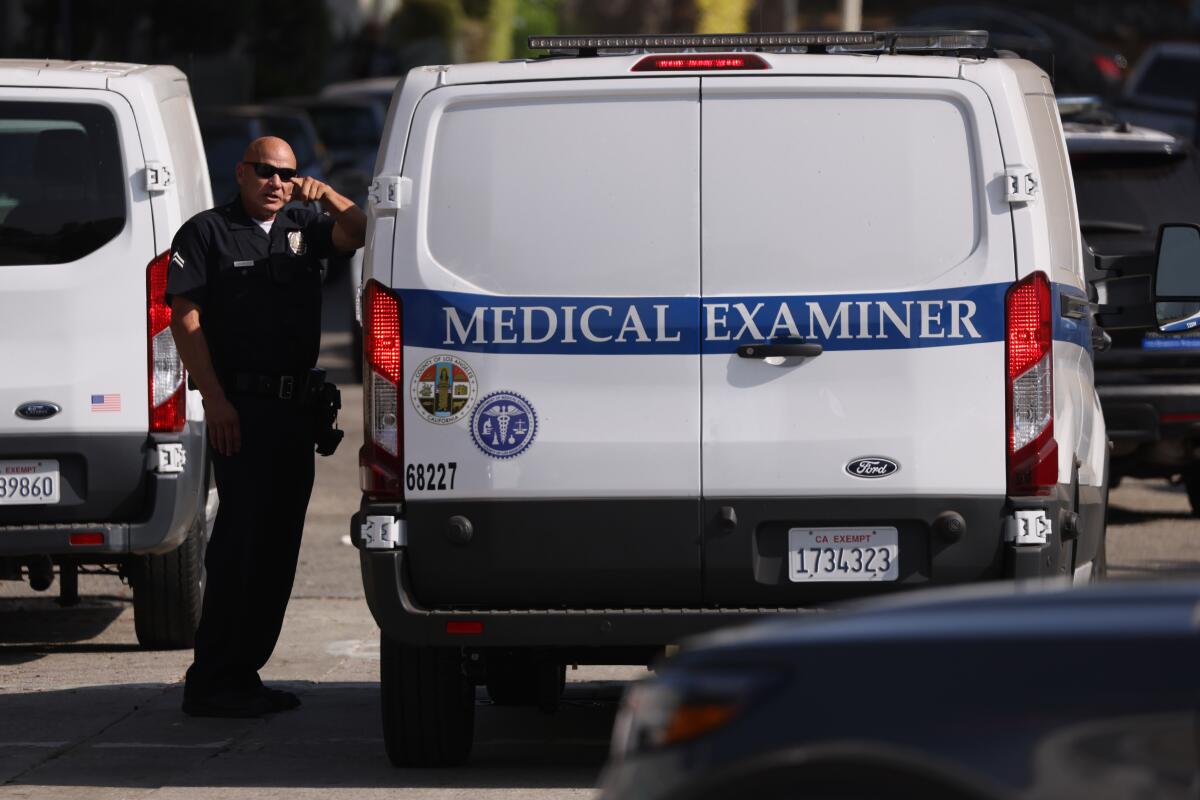 A police officer interacts next to a medical examiner van where three people were shot dead in Hollywood.