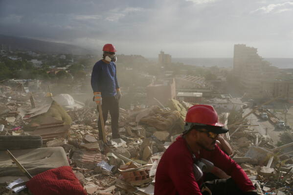 Rescue workers and volunteers search through the rubble of a building collapsed during the earthquakes in La Guaira, Venezuela, July 6, 2026. (AP Photo/Ariana Cubillos, File)