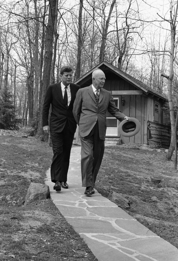 President John Kennedy and former President Dwight Eisenhower walks along a flagstone path, in perfect step at Camp David, atop of mountain near Thurmont, Maryland on April 22, 1961 after they flew there to discuss the Cuban crisis. In background is one of the lodges at the camp. (AP Photo, File)