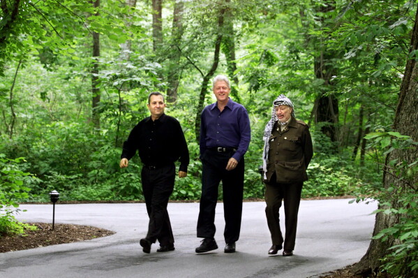 President Bill Clinton, Israeli Prime Minister Ehud Barak, left, and Palestinian leader Yasser Arafat, right, walk on the grounds of Camp David, Md., Tuesday July 11, 2000, at the start of the Mideast summit. (AP Photo/Ron Edmonds, File)