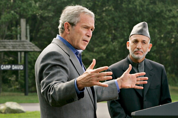 President George W. Bush, left, accompanied by Afghanistan's President Hamid Karzai, right, gestures during their joint press conference, Monday, Aug. 6, 2007, at Camp David, Md. (AP Photo/J. Scott Applewhite, File)