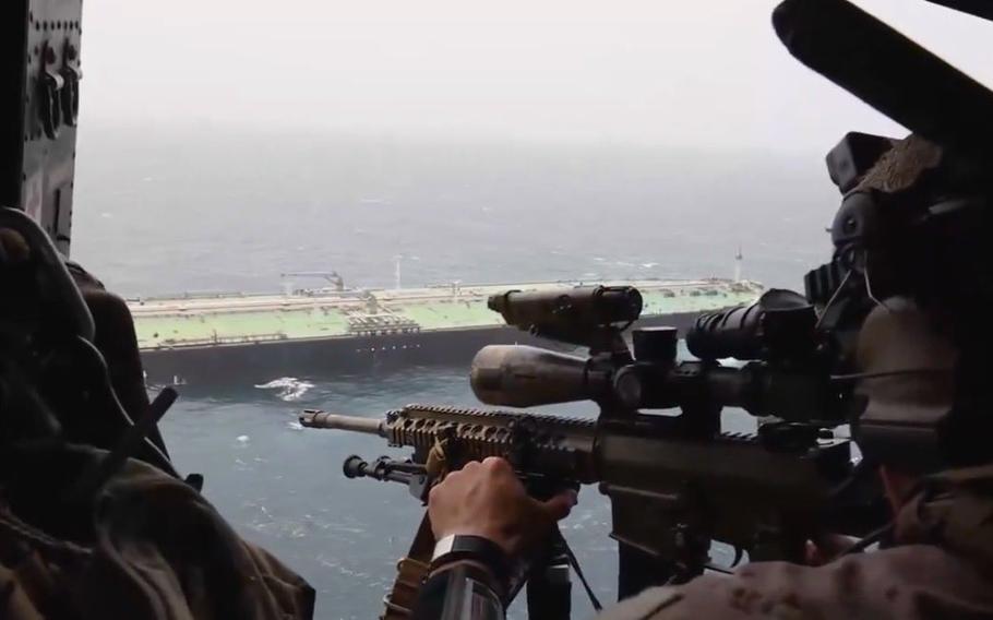 Armed troops observe the Strait of Hormuz from an aircraft.