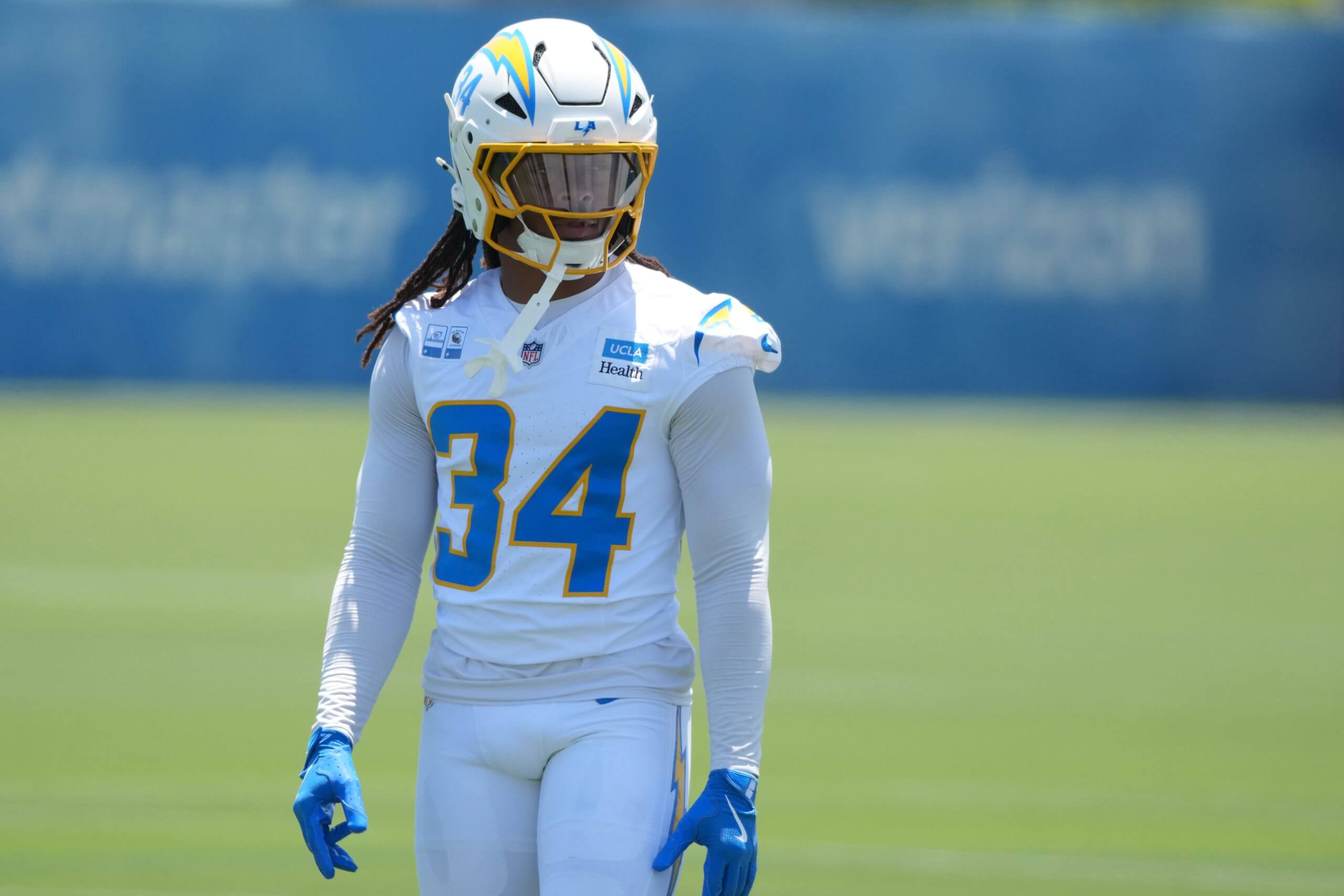 Los Angeles Chargers running back Keaton Mitchell, wearing a white No. 34 jersey and white helmet, stands on the practice field during the Chargers' mandatory minicamp in June.
