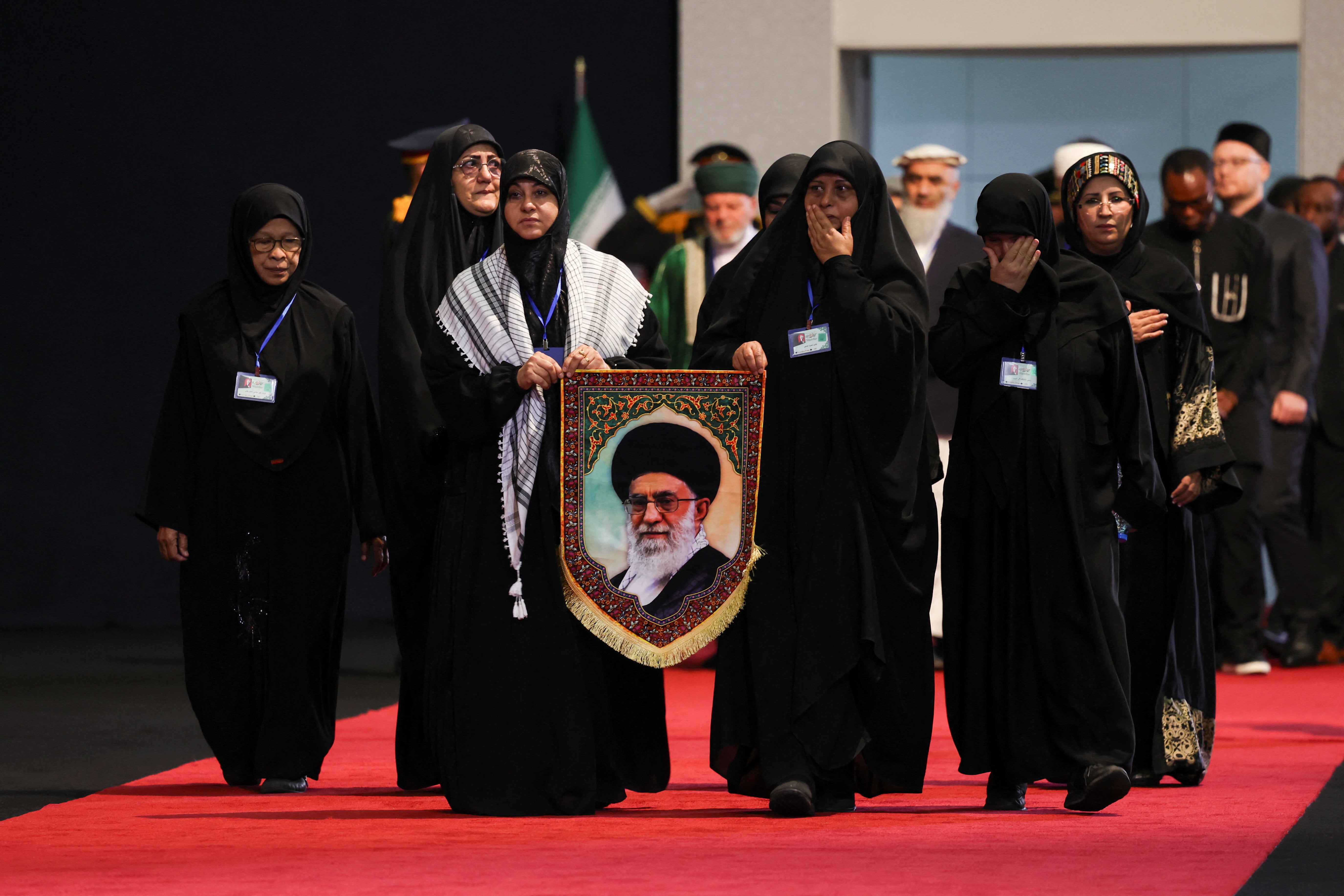 Women react as they walk to pay their respects near the coffins of Iran's late Supreme Leader Ayatollah Ali Khamenei and his family members