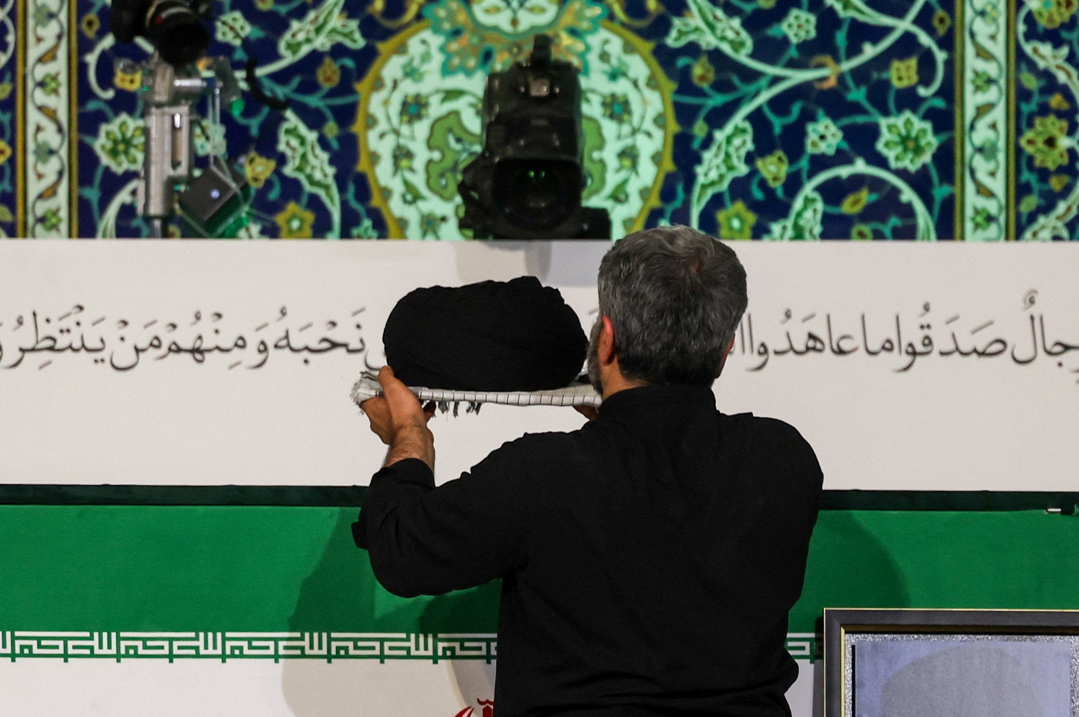 A man places a turban over the coffin of Iran's late Supreme Leader Ayatollah Ali Khamenei on Friday