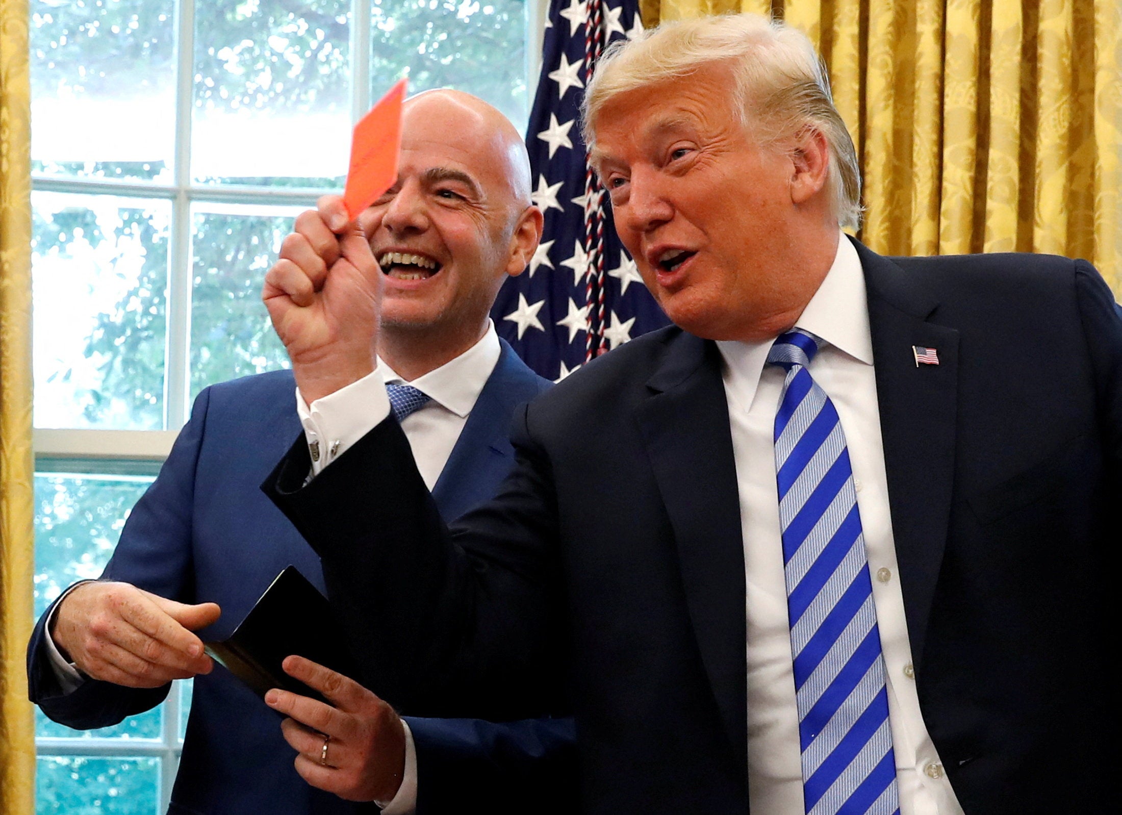 US president Donald Trump holds up a red card as he meets with Fifa counterpart Gianni Infantino before the World Cup