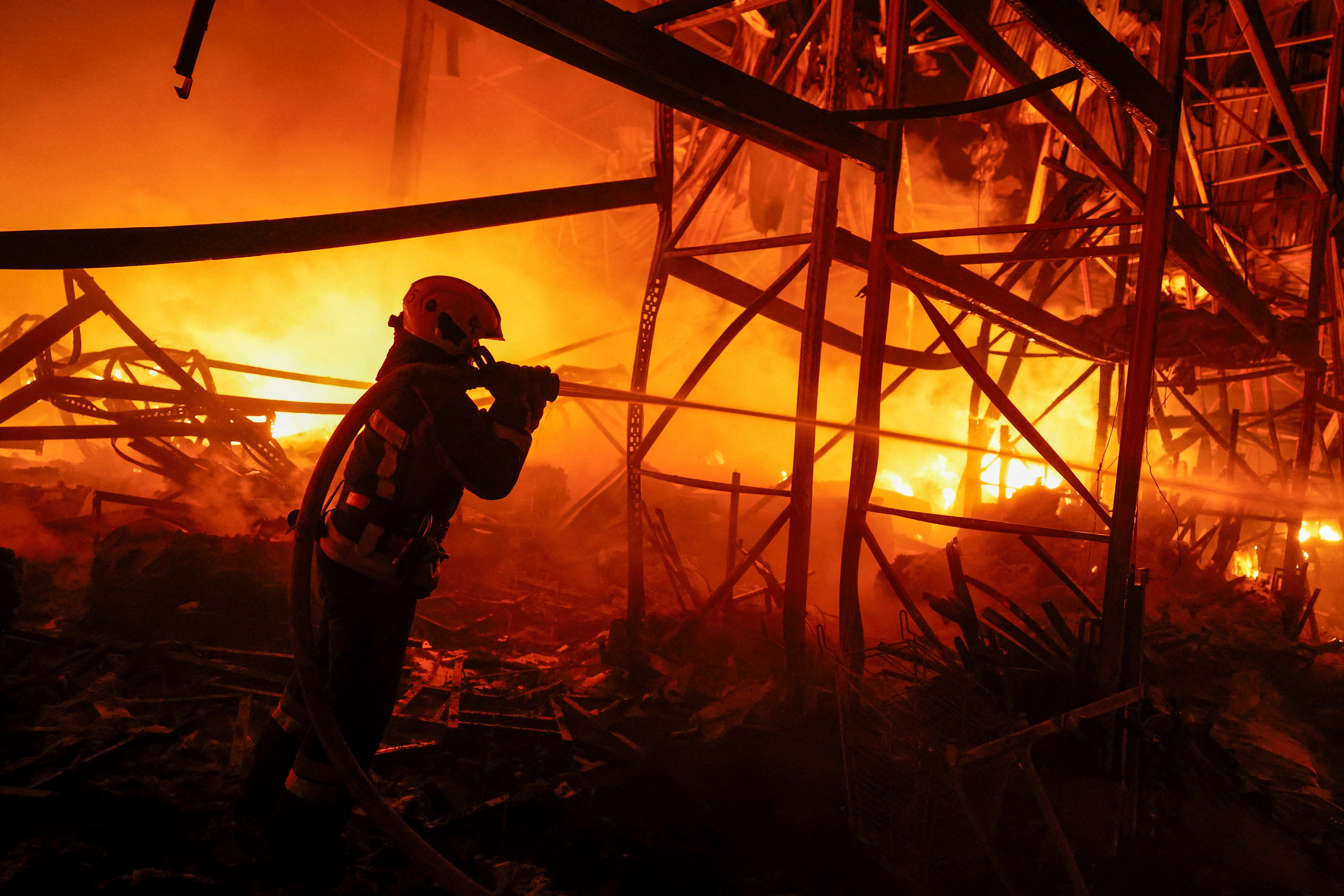 A firefighter works at a compound of a warehouse damaged during Russian missile strikes, amid Russia's attack on Ukraine, in Kyiv
