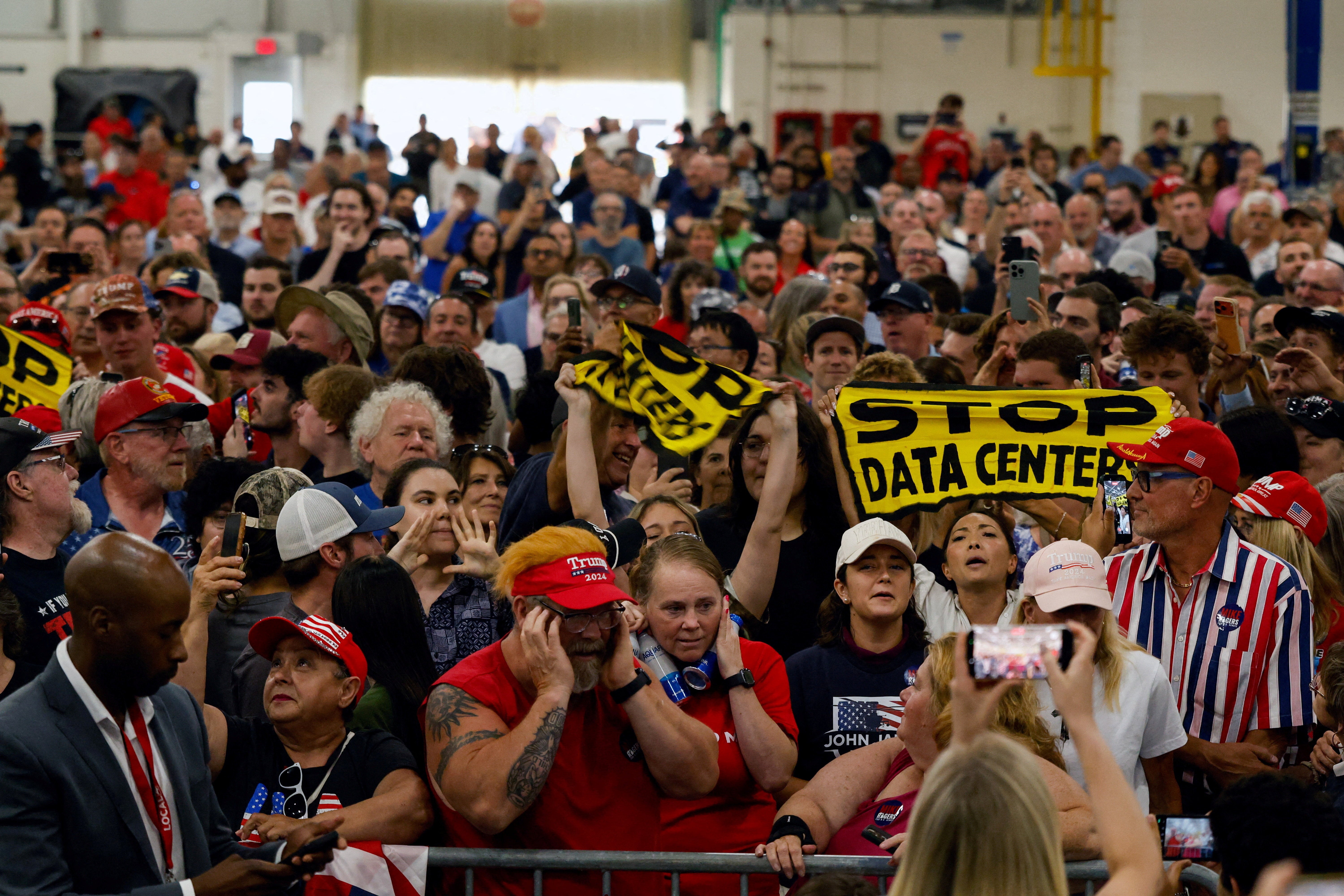 Protestors hold up 'Stop data centers' signs, on the day of Trump's speech in Michigan