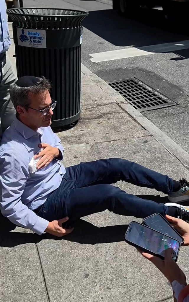 Moshe Grunhaus, a Jewish man, is seen wounded and sitting on the sidewalk on Amsterdam Avenue and West 86th Street.