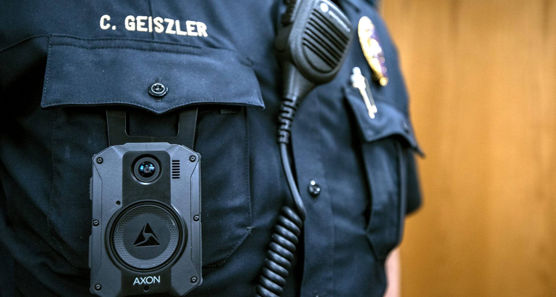 A body camera is clipped onto the pocket of a police officer's uniform.