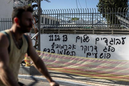 A biker rides past a graffiti text found in Tel Aviv inciting against Israeli television broadcasters 11, 12 and 13, in June. Credit: Hadas Parush A biker rides past a graffiti text found in Tel Aviv inciting against Israeli television broadcasters 11, 12 and 13, in June.