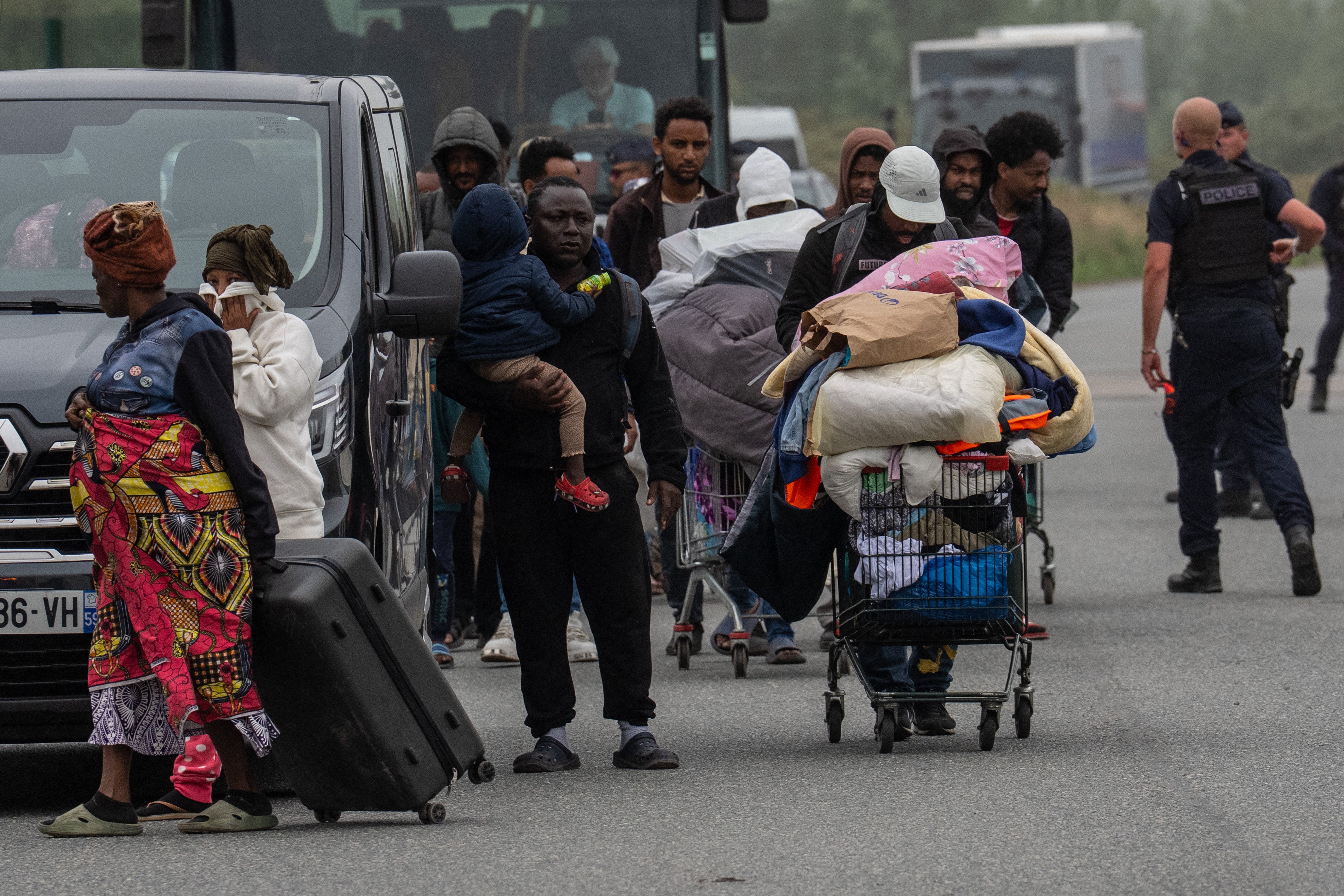 Migrants leave an area of their camp that was cleared by French authorities on 2 July 2026 in Loon-Plage, France.