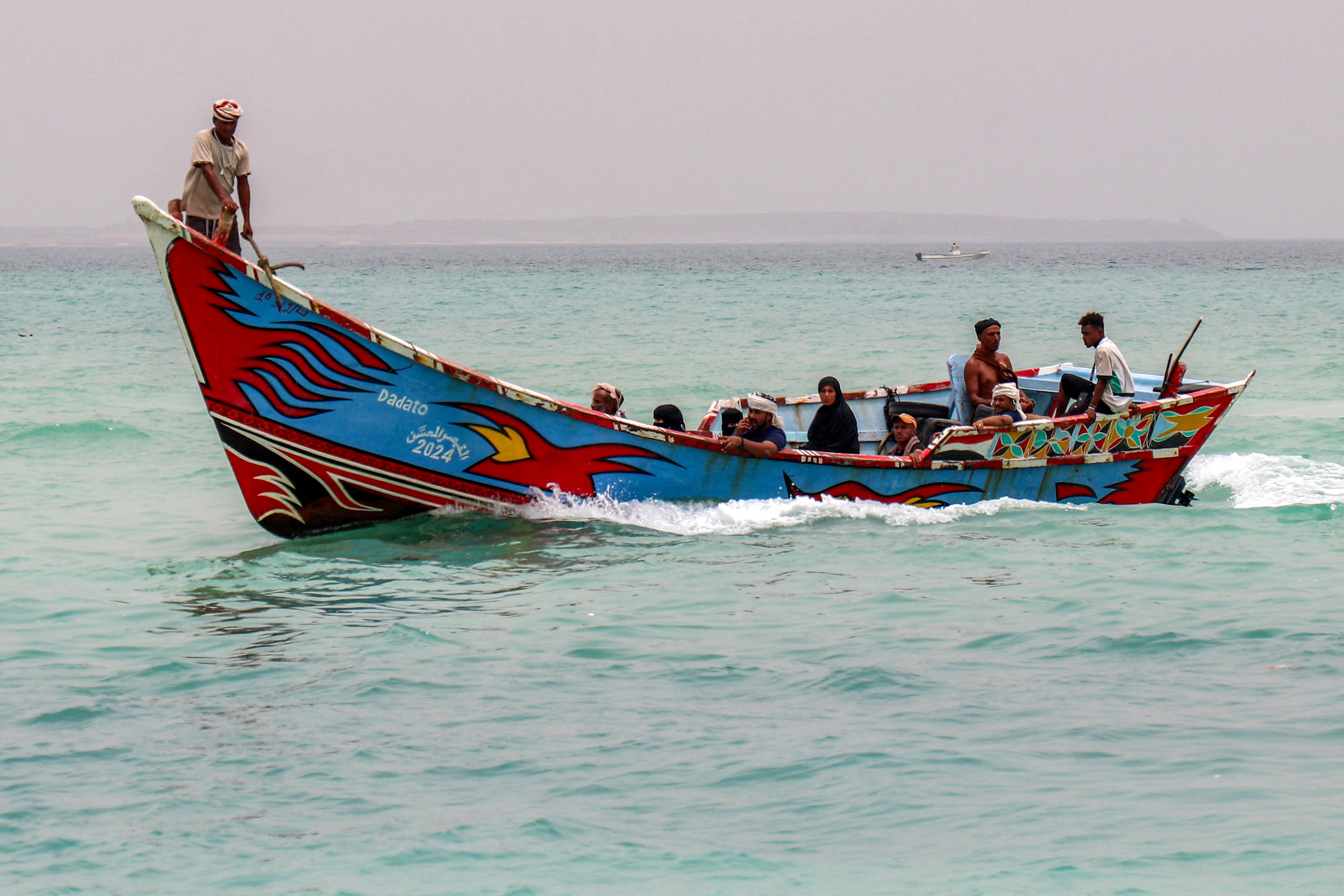 People sit in a fishing boat sailing the Bab el-Mandeb Strait off of Yemen's southern Taiz province on 25 July 2026