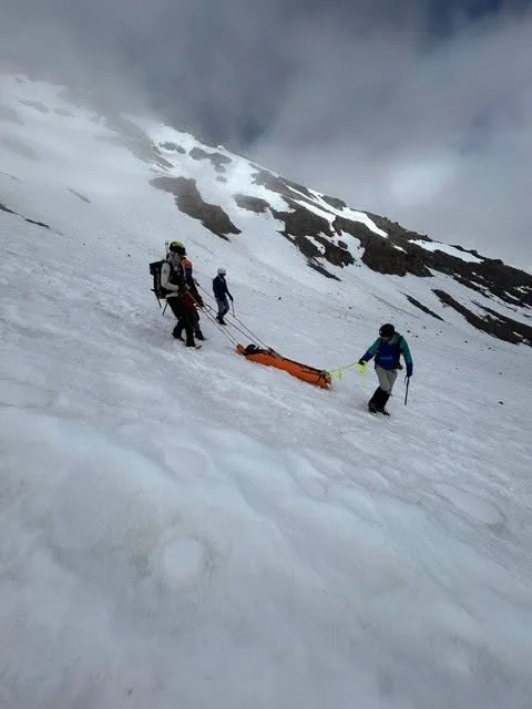 Rescue workers pulling a stretcher across a snow-covered mountain. Facebook/U.S. Forest Service – Shasta-Trinity National Forest