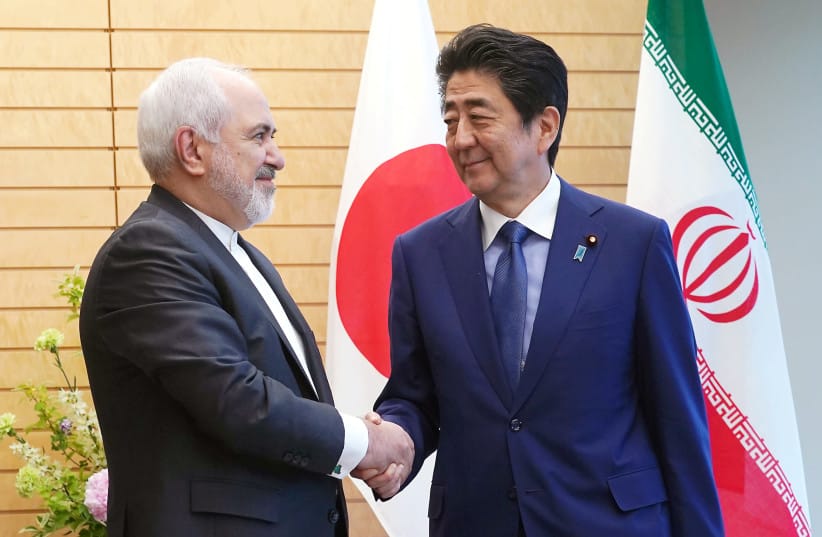 Iranian Foreign Minister Mohammad Javad Zarif, left, and Japanese Prime Minister Shinzo Abe, right, shake hands at Abe's official residence in Tokyo Thursday, May 16, 2019.