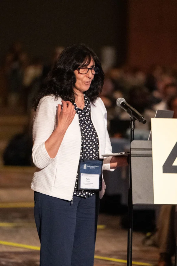 A woman stands at a microphone. 