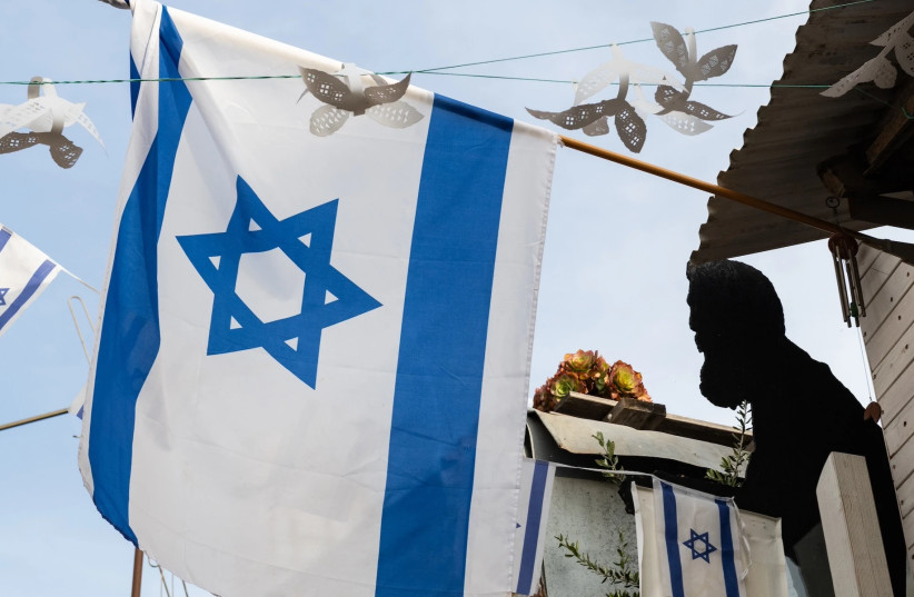 A silhouette of Theodor Herzl, the founder of modern Zionism, is displayed near a flag of the state of Israel on a building in Jerusalem.