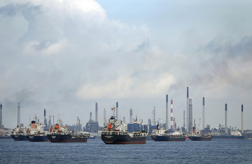 Ships are seen anchored in front of a refinery on Singapore's Bukom Island, through the Malacca Strait, July 6, 2014