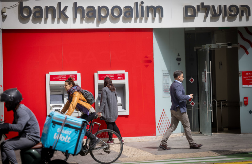 A woman takes out money from a Bank HaPoalim ATM machiine in Tel Aviv on March 25, 2025