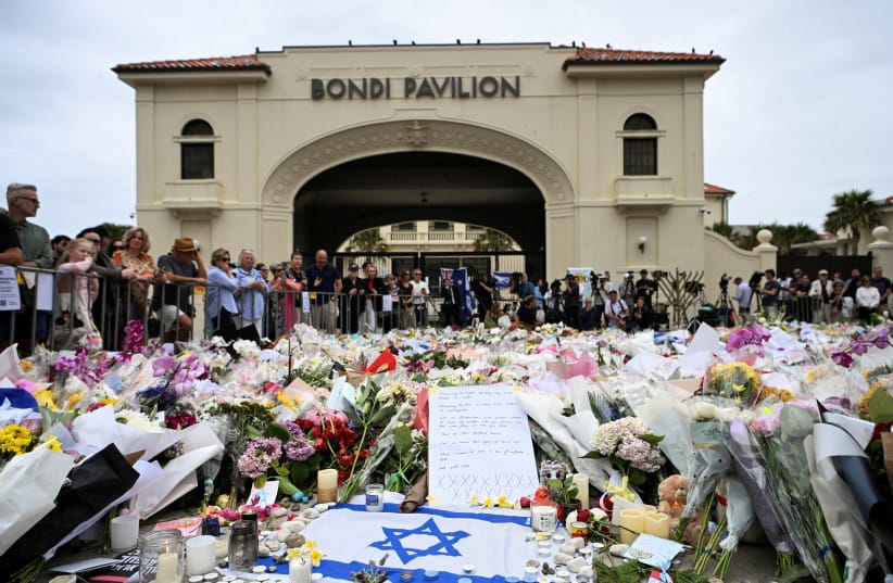 People stand near flowers laid as a tribute at Bondi Beach to honour the victims of a mass shooting that targeted a Hanukkah celebration at Bondi Beach on Sunday, in Sydney, Australia, December 16, 2025.