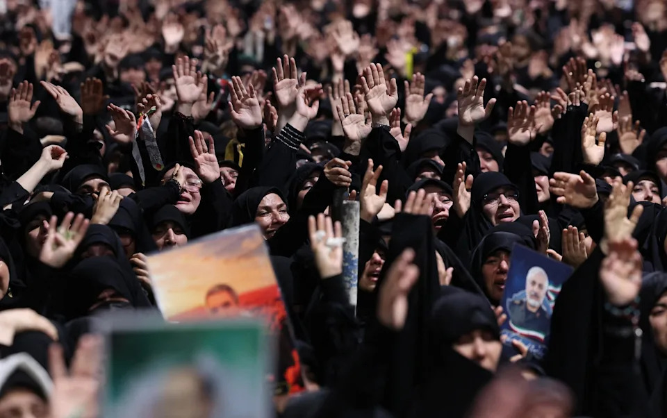 A crowd of mourners gathers around the coffin during the ceremonies