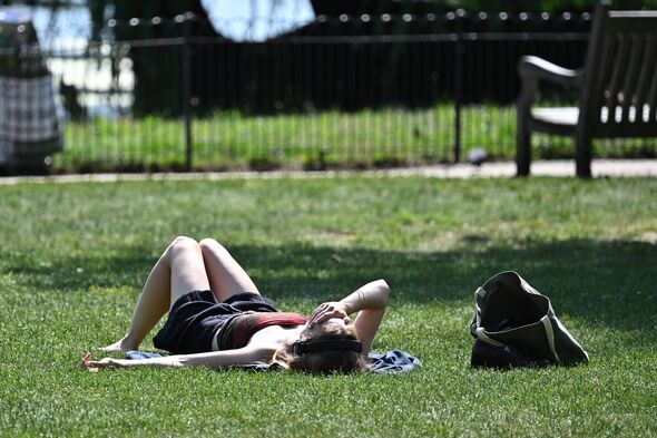 LONDON, ENGLAND - JUNE 22: A woman covers her eyes as she lays in the sun during the sunny hot weather in St James's Park on Jun