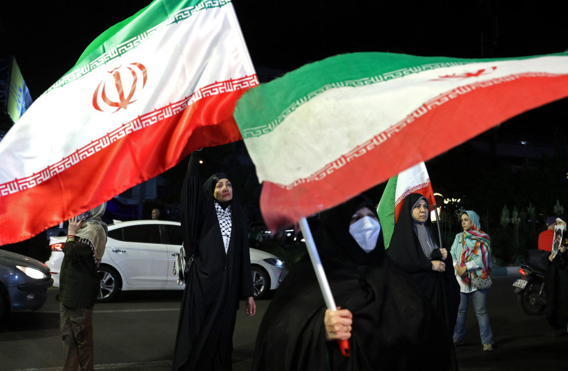 Women hold Iran's national flags during an anti-US and Israel protest at the Hafte Tir Square in Tehran on May 17, 2026.