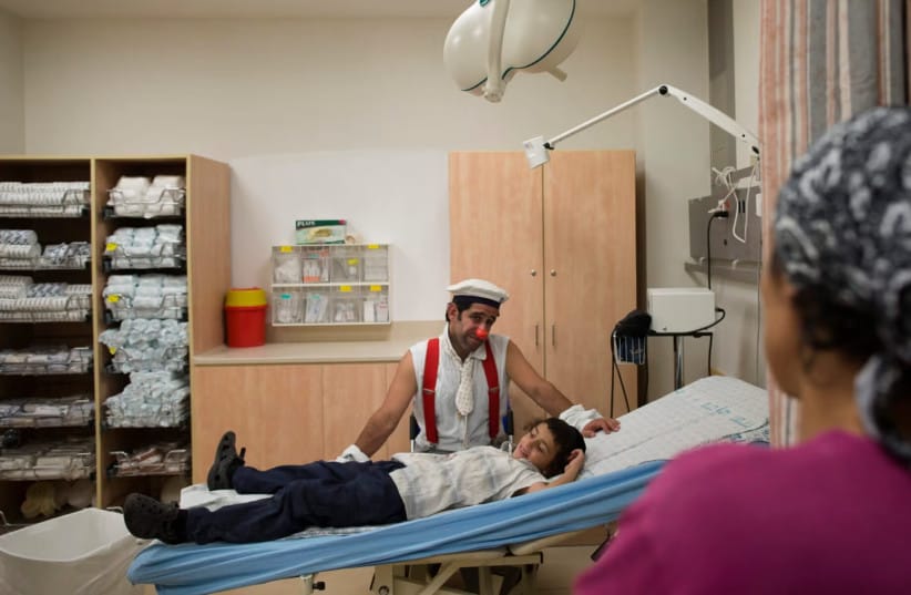 Medical clown David Barashi, known as Dush the Clown, interacts with a child as he receives medical care as part of the Dream Doctors Project at Hadassah Hospital in Jerusalem, June 24, 2013.