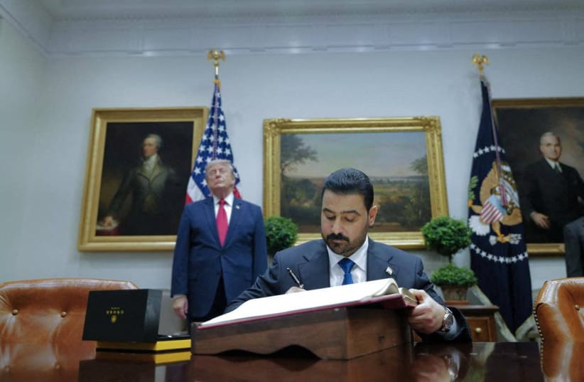 Iraqi Prime Minister Ali al-Zaidi writes in a book as U.S. President Donald Trump stands behind him at the White House in Washington, D.C., U.S., July 14, 2026.