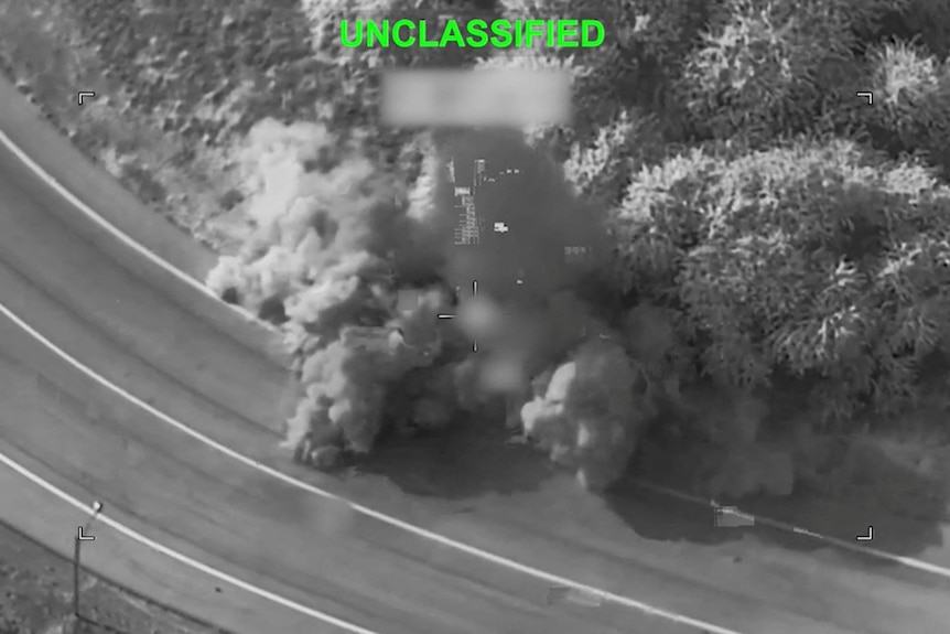 Night-time vision - shot from above - shows smoke rising from a road.