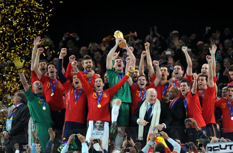 Spain's goalkeeper Iker Casillas (C) raises the trophy as Spain's national football team players celebrate with FIFA President Sepp Blatter (5thR) and South Africas President Jacob Zuma (4thR) winning the 2010 World Cup football final Netherlands vs. Spain on July 11, 2010 at Soccer City stadium in Soweto, suburban Johannesburg. NO PUSH TO MOBILE / MOBILE USE SOLELY WITHIN EDITORIAL ARTICLE - AFP PHOTO / GABRIEL BOUYS (Photo by GABRIEL BOUYS / AFP)