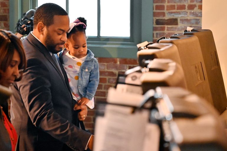 14-month-old Justice Booker looks on as her father, Kentucky Democratic candidate for Senate Charles Booker casts his early vote in the midterm election in Louisville, Ky., Thursday, Nov. 3, 2022. (AP Photo/Timothy D. Easley)