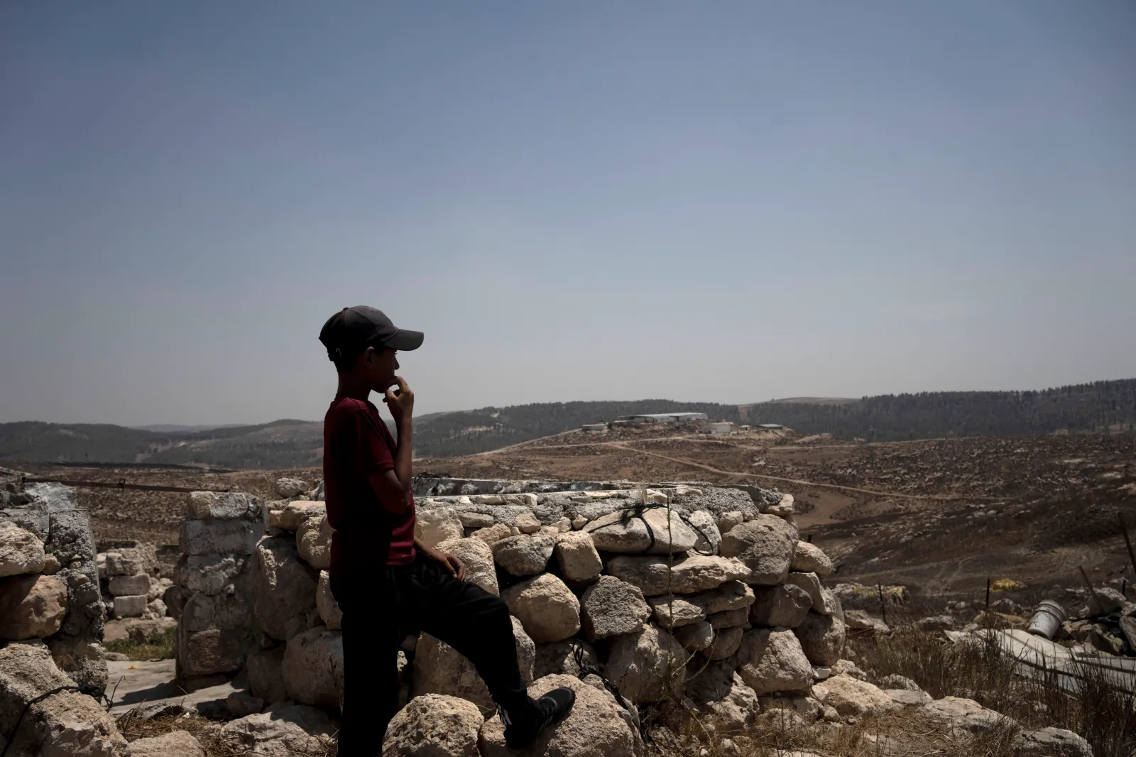 A child stands in the ruins of a stone house in the West Bank village of Khirbet Zanuta, overlooking the Meitarim Farm, owned by sanctioned settler Yinon Levy on August 27, 2024. (AP Photo/Maya Alleruzzo)
