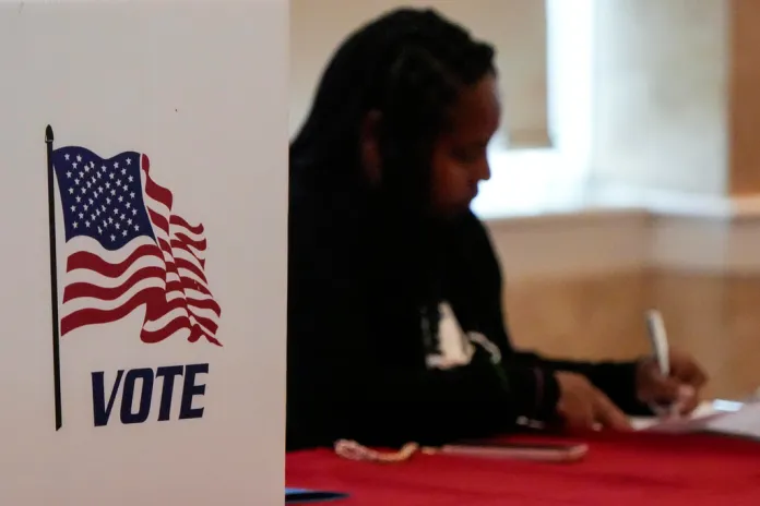 A Fulton County staff member works as people vote.